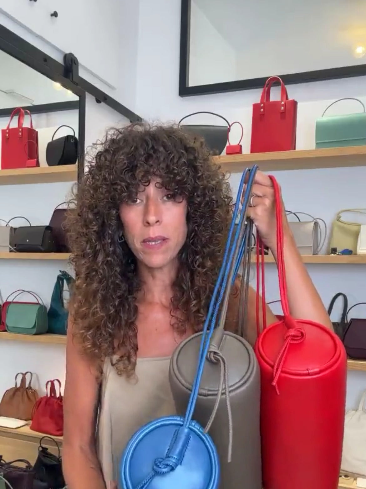 Irene con varios bolsos tubulares de piel de colores en la boutique de Labienhecha durante el directo de San Juan